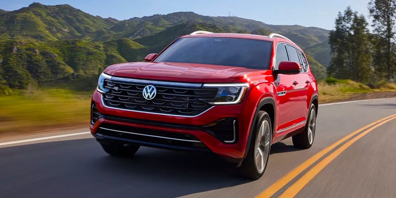 A red 2024 Volkswagen Atlas driving down the highway on a sunny day