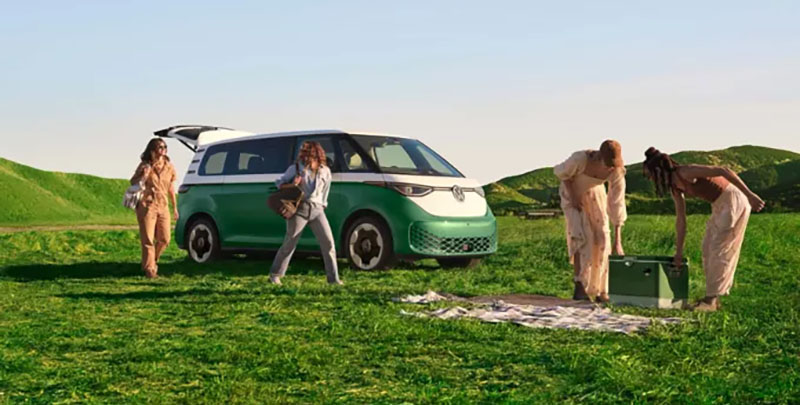 A group of women unpacking picnic items from their all-new Volkswagen ID Buzz that is parked in a field on a sunny day