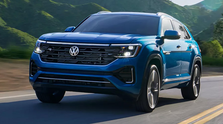 A blue 2025 Volkswagen Atlas driving down the highway on a sunny day